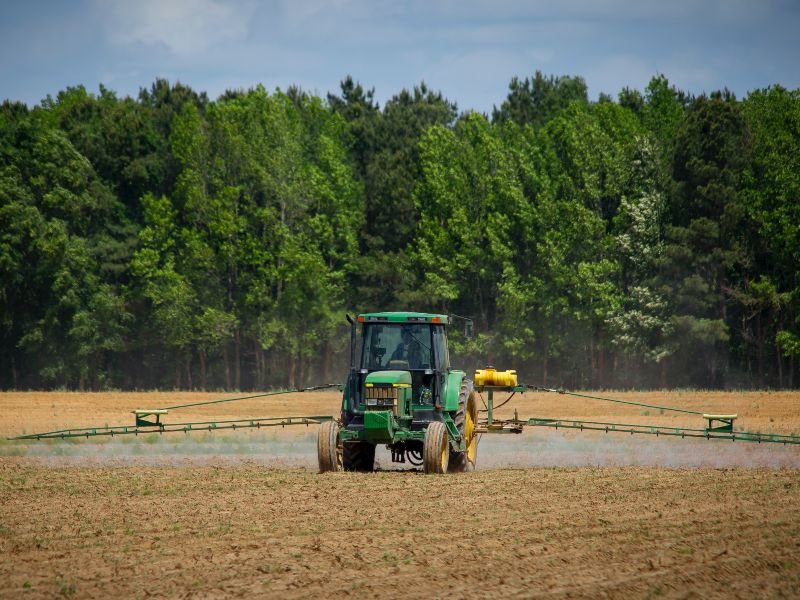 Un tractor verde tira agroquímicos en un campo