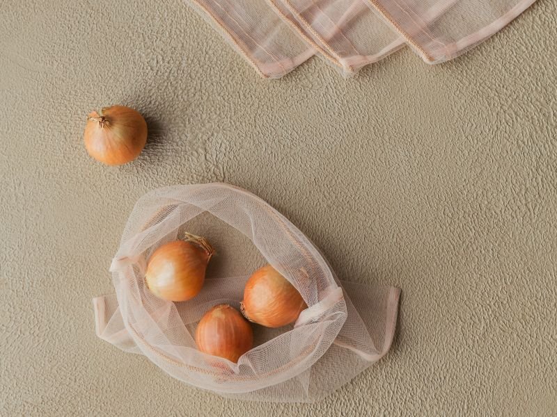 Bolsas de tela de red con unas cebollas dentro