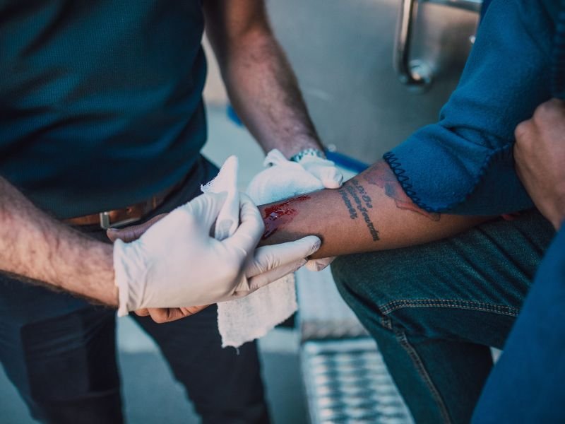 Un médico cura la herida del brazo de un hombre.