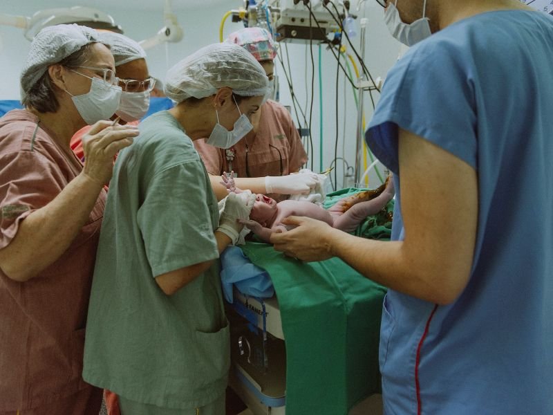 EScena de parto. Unas enfermeras toman en brazos un bebé recién nacido