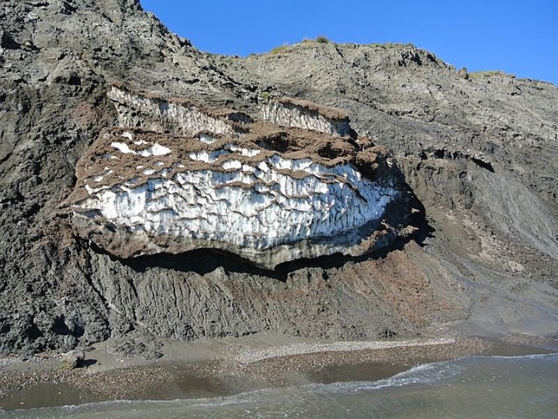 Una montaña gris con una capa blanca en el medio que se la conoce como permafrost