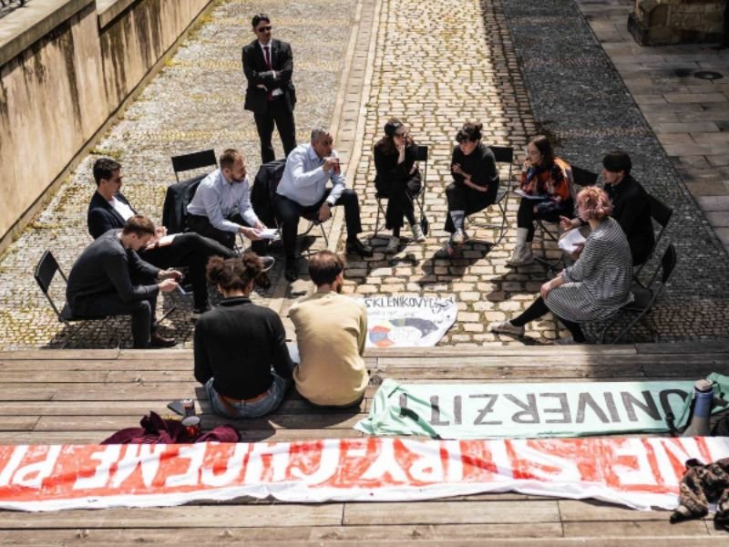 Estudiantes de la República Checha sentados en ronda. Hablan con el Ministro de Comercio e Industria. Hay carteles de la campaña End fossil: Occupy!