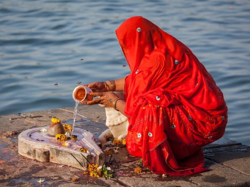 Una persona hinduista haciendo un rito al lado del río.