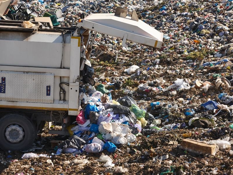 Un camión de basura descarga residuos en un basural a cielo abierto