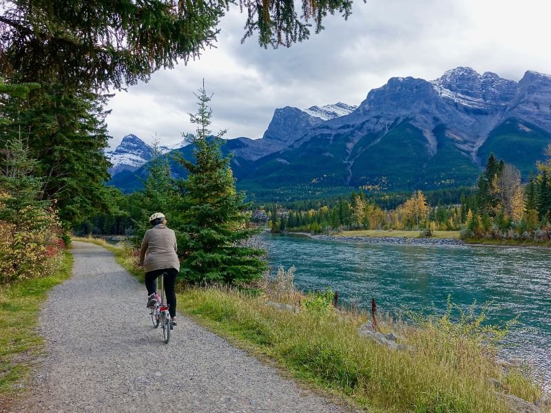 Un ciclista en un camino al lado de un lago y una montaña