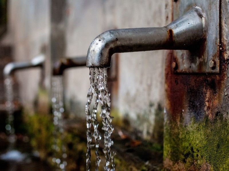 Un grifo o canilla abierto y unas gotas de agua cayendo