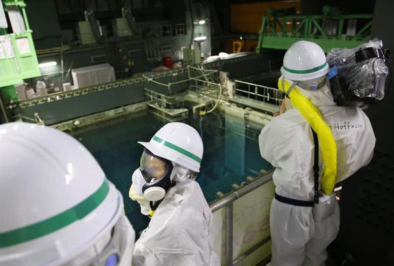 personas vestidas con trajes contra radiación en la planta de fukushima viendo aguas residuales y radiactivas