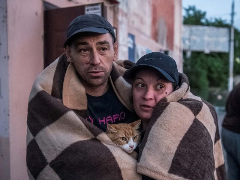 Los residentes locales reaccionan después de su evacuación de un área inundada después de que se rompiera la represa