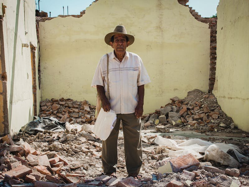 Un hombre en medio de una casa destruida por un terremoto