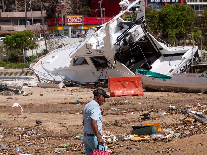 Un hombre camina cerca de un barco dañado entre escombros en la playa tras el paso del huracán Otis, en Acapulco, México