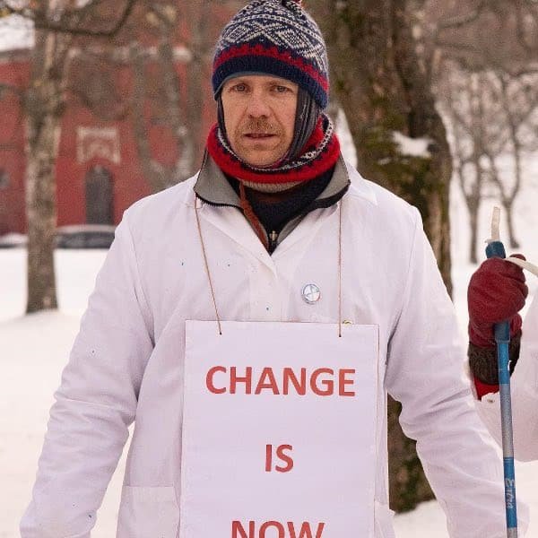 Un profesional de la ciencia en una movilización con un cartel que dice "El cambio es ahora".