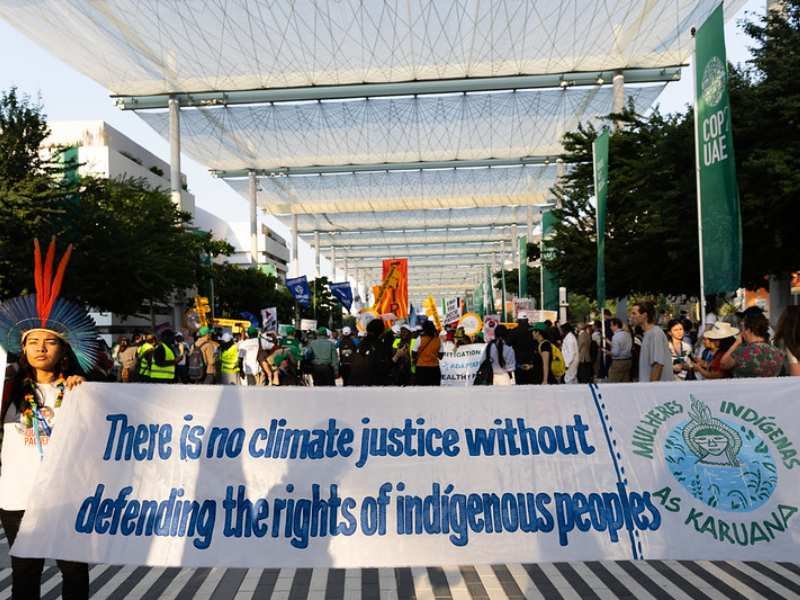 Manifestación en la COP28 donde personas muestran un cartel que dice: "No hay justicia climática sin defender los derechos de las personas indígenas".