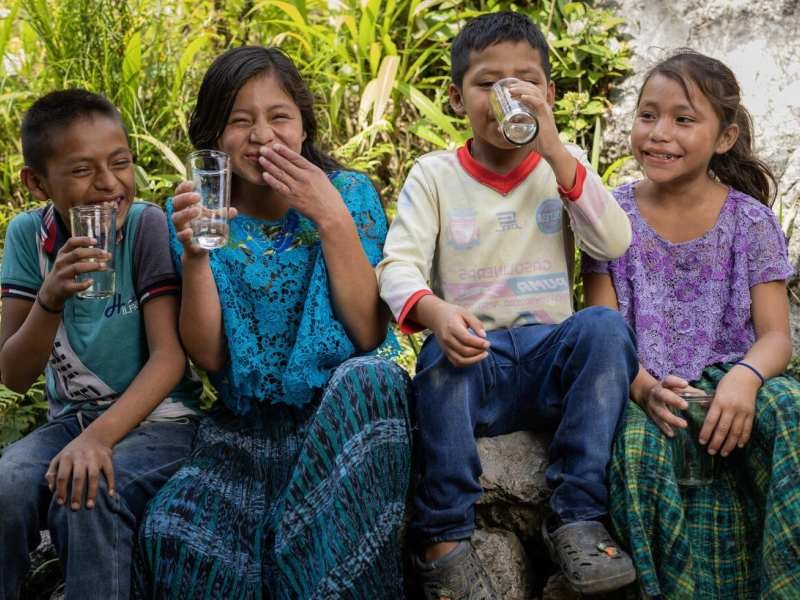 Cuatro chicos latinoamericanos bebiendo agua, fotografiados por UNICEF.