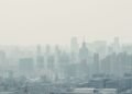 Niebla tóxica sobre una ciudad con edificios, representando la contaminación del aire que afecta la salud infantil.