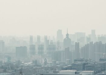 Niebla tóxica sobre una ciudad con edificios, representando la contaminación del aire que afecta la salud infantil.