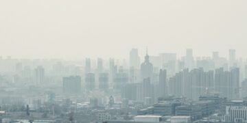 Niebla tóxica sobre una ciudad con edificios, representando la contaminación del aire que afecta la salud infantil.