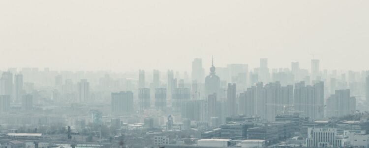 Niebla tóxica sobre una ciudad con edificios, representando la contaminación del aire que afecta la salud infantil.