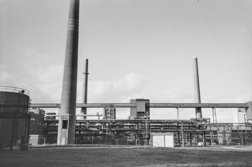 Refinería petrolera de mediados del siglo XX con chimeneas emitiendo humo, época en que gobiernos conocían riesgos del calent