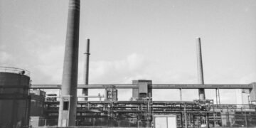 Refinería petrolera de mediados del siglo XX con chimeneas emitiendo humo, época en que gobiernos conocían riesgos del calent