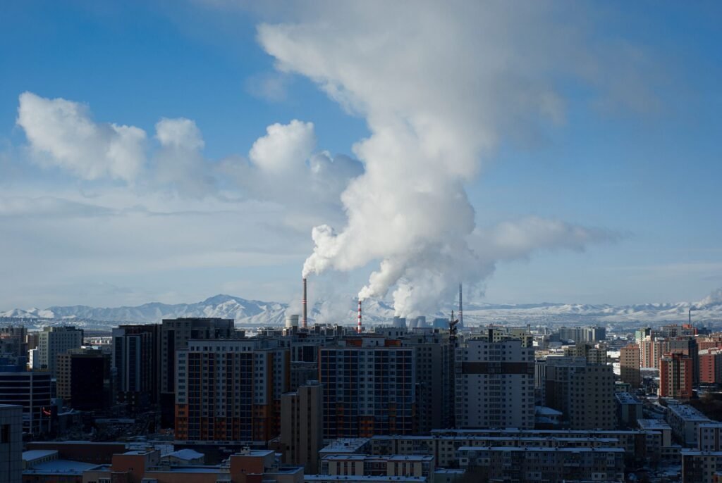Vista de una ciudad con contaminación atmosférica visible y emisiones industriales en el horizonte.