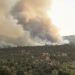 Paisaje de incendio forestal con humo denso cubriendo bosques en España durante la ola de calor extrema.