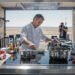 Chef profesional cocinando en cocina moderna con tecnología de inducción eléctrica.