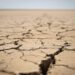 Tierra agrietada por sequía extrema bajo el sol intenso, imagen representativa del calor extremo proyectado.