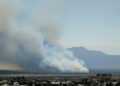 Paisaje de bosque nativo argentino con humo de incendio forestal al fondo.