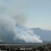 Paisaje de bosque nativo argentino con humo de incendio forestal al fondo.