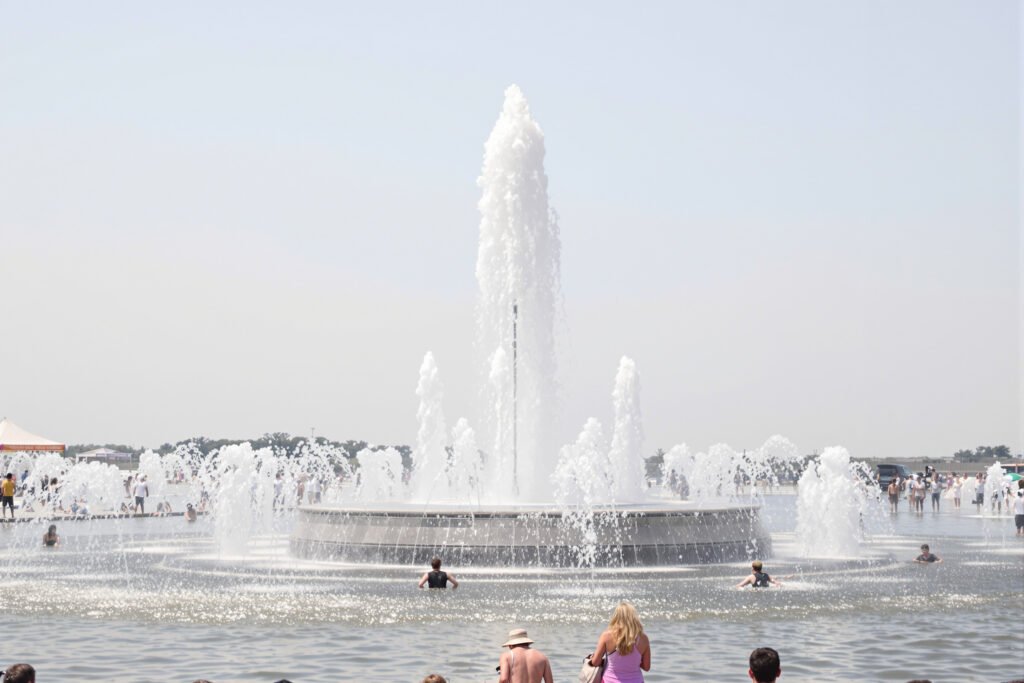Una fuente pública en una plaza europea durante una ola de calor extremo, con personas buscando alivio del calor sofocante.