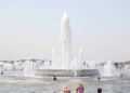 Una fuente pública en una plaza europea durante una ola de calor extremo, con personas buscando alivio del calor sofocante.