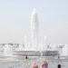 Una fuente pública en una plaza europea durante una ola de calor extremo, con personas buscando alivio del calor sofocante.