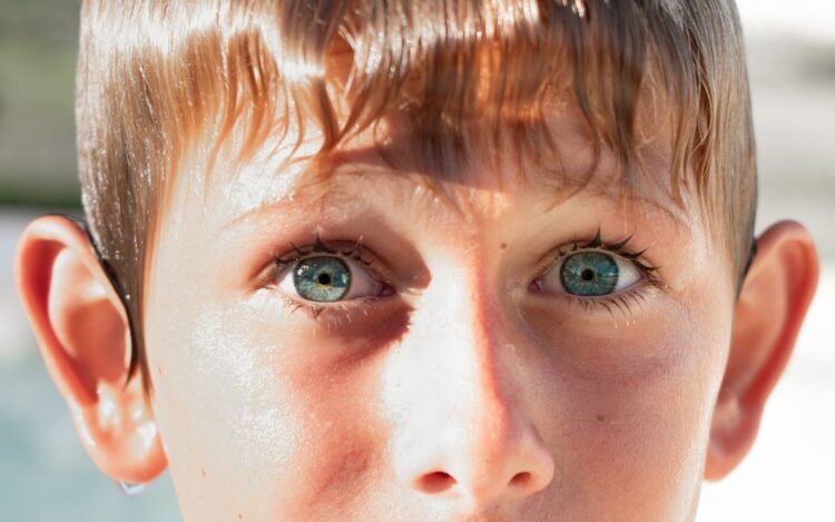Niño bebiendo agua bajo el sol en un día de calor extremo, evidencia del estrés térmico que afecta a la infancia por el cambi