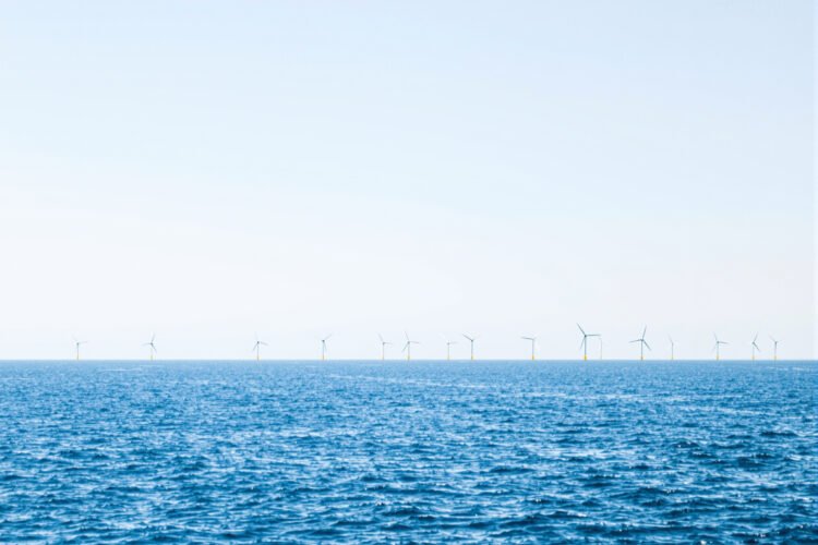 Parque eólico marino en el mar del Norte con aerogeneradores sobre el océano al atardecer.