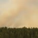 Columna de humo elevándose sobre un paisaje forestal afectado por incendio, representando la magnitud del peor incendio de la