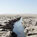 Lecho seco y agrietado de un río europeo durante sequía extrema, con barcos varados en el horizonte.