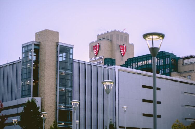Fachada acristalada de un hospital moderno con luz solar reflejándose en las ventanas.