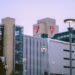 Fachada acristalada de un hospital moderno con luz solar reflejándose en las ventanas.