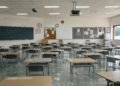 Aula de escuela inundada con bancos vacíos, símbolo del impacto del clima en la educación global.