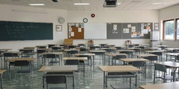 Aula de escuela inundada con bancos vacíos, símbolo del impacto del clima en la educación global.