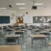 Aula de escuela inundada con bancos vacíos, símbolo del impacto del clima en la educación global.