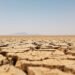 Tierra agrietada por sequía extrema bajo sol intenso, ilustrando el récord de temperatura global de agosto de 2026.