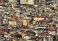 Paneles solares en techos de barrio urbano denso, representando la expansión solar descontrolada en países en desarrollo.