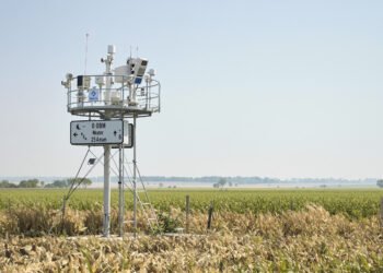Estación meteorológica comunitaria en paisaje rural latinoamericano donde comunidades generan datos climáticos locales.