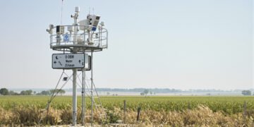 Estación meteorológica comunitaria en paisaje rural latinoamericano donde comunidades generan datos climáticos locales.