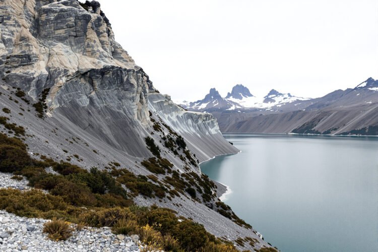 Vista de un desprendimiento de ladera en cerro patagónico junto a un lago, con vegetación arrastrada hacia el agua.