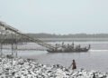 Draga minera ilegal operando en un río de la Amazonía peruana, extrayendo oro de los sedimentos.