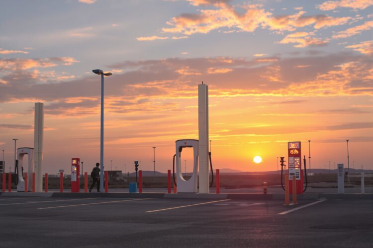 Estación de carga para vehículos eléctricos en China al atardecer, símbolo de la transición energética que impulsa la caída d