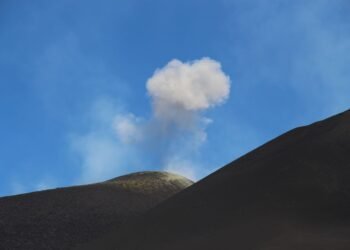 Columna de ceniza y humo emergiendo desde un volcán activo en erupción.
