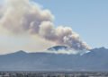Humo de incendio forestal en zona montañosa de Córdoba, Argentina, con vegetación de pastizal.